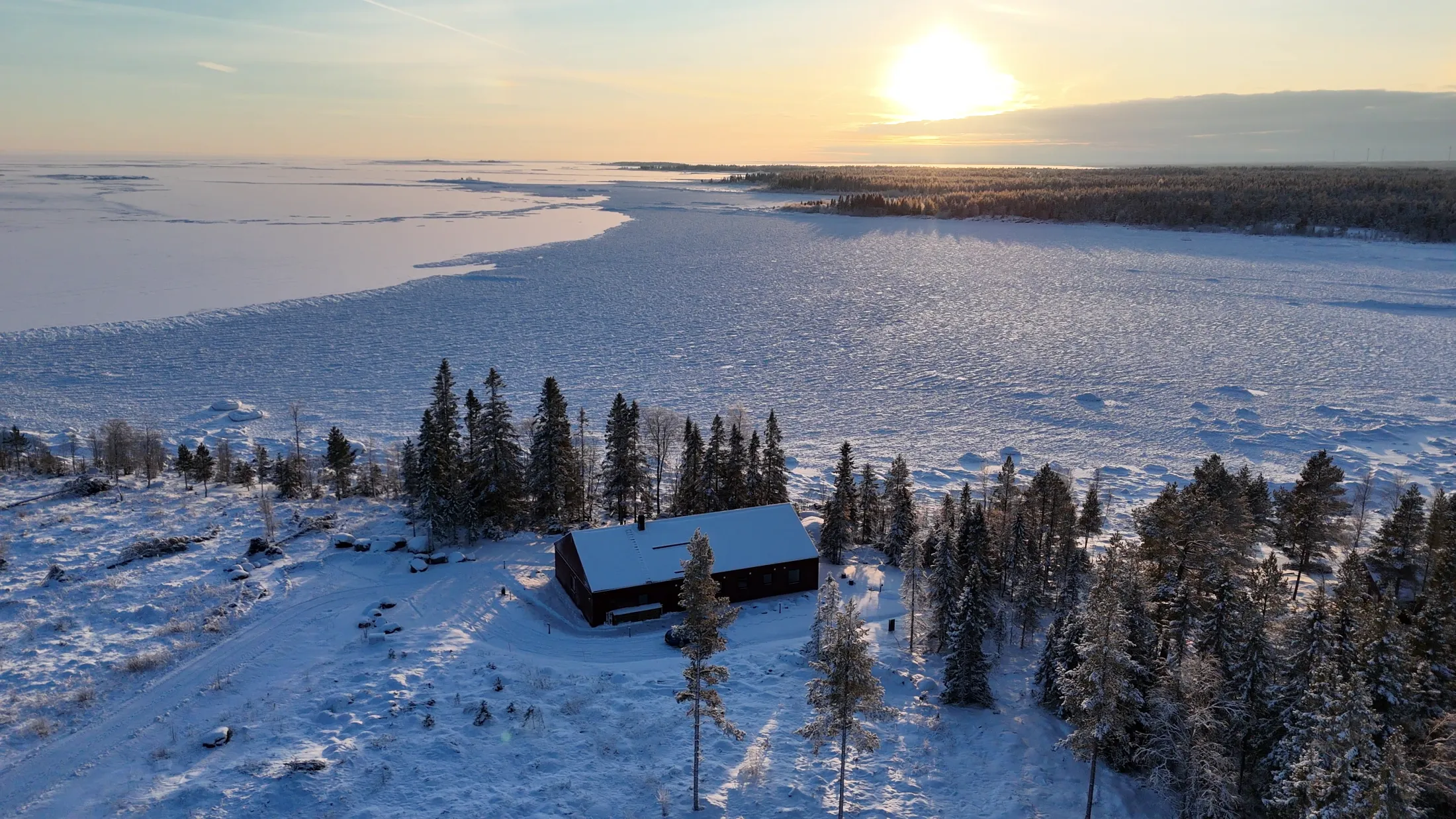 Drone photo of Villa Östersjön at the forest edge beside the winter Baltic Sea