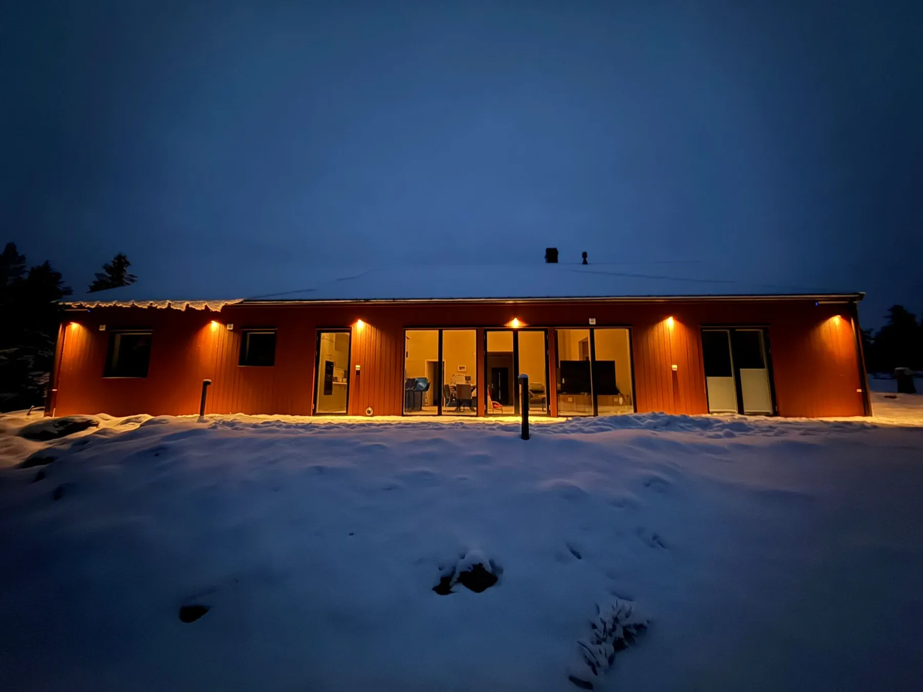 Lit glass front of Villa Östersjön in snow