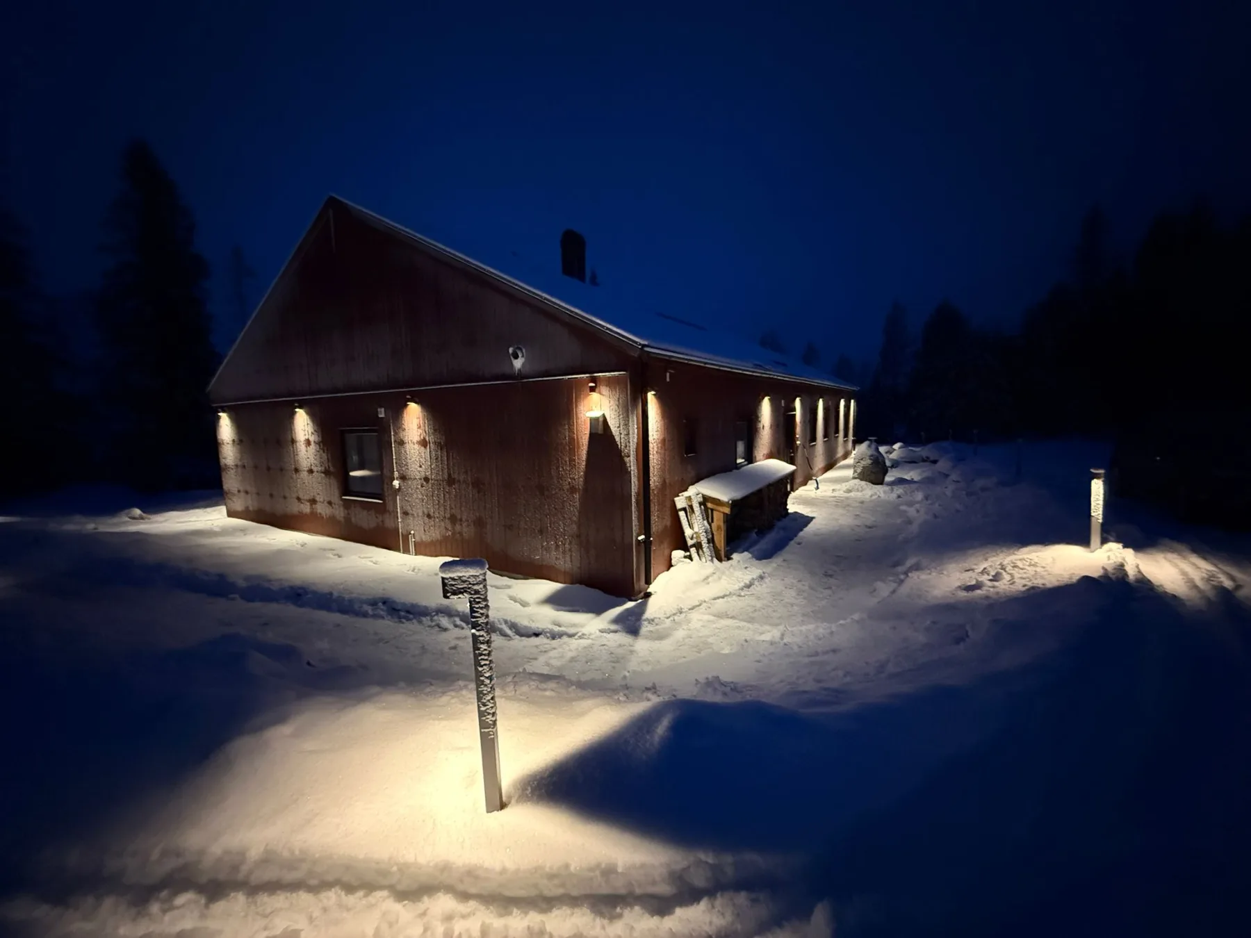 Long lit wooden facade of Villa Östersjön in winter