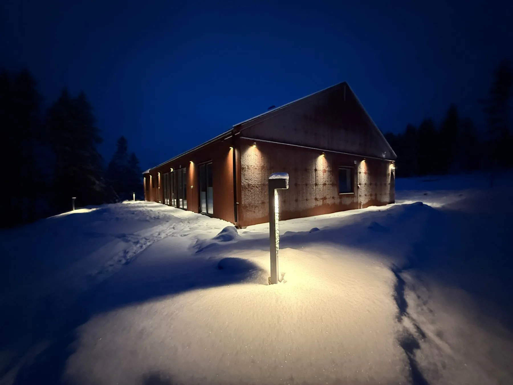 Villa Östersjön in snow with a lit path in blue evening light